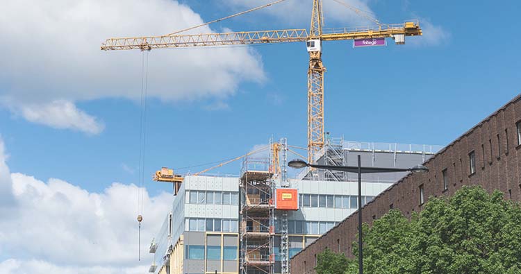 Mellan några fastigheter eller kontor skyns en stor byggkran,