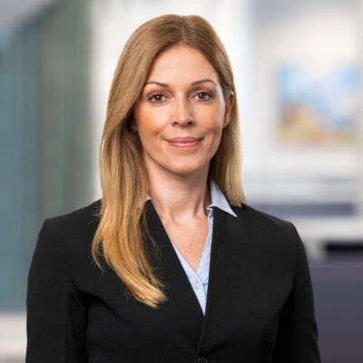 Porträtt på en leende kvinna i mörk kavaj som ser in i kameran.