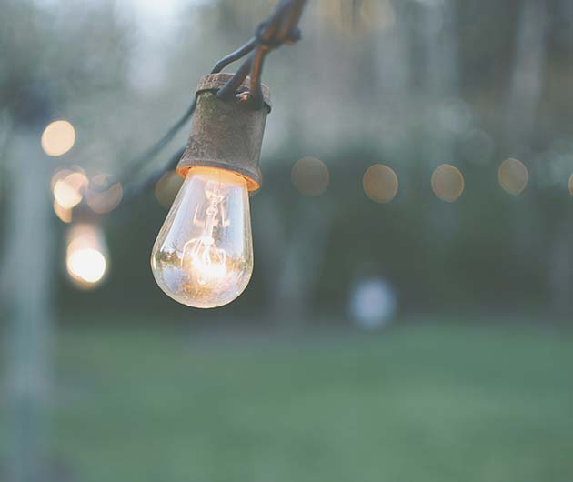 Detalj på en hängande sladd med lysande glödlampor utomhus.
