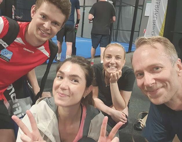 Fyra personer ser in i kameran och ser glada ut efter en padelmatch.