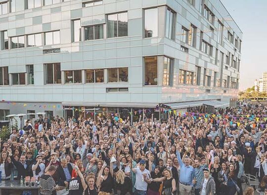 Fest utomhus med väldigt mycket folk, i bakgrunden syns ett kontorshus och längst bort en byggkran.