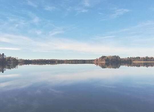 Somrig bild av en blå sjö med blå himmel och en smal landremsai horisonten.