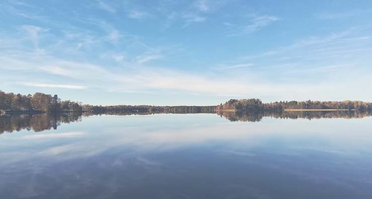 Somrig bild av en blå sjö med blå himmel och en smal landremsai horisonten.