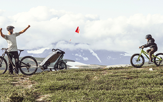 En pappa och en son är ute och cyklar i naturen.