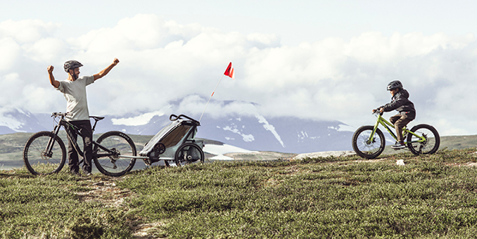 En pappa och en son är ute och cyklar i naturen.