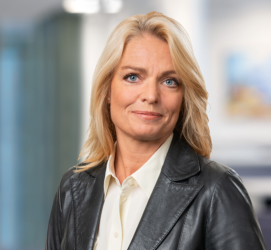 Porträtt på blond kvinna i svart skinnkavaj och vit skjorta.