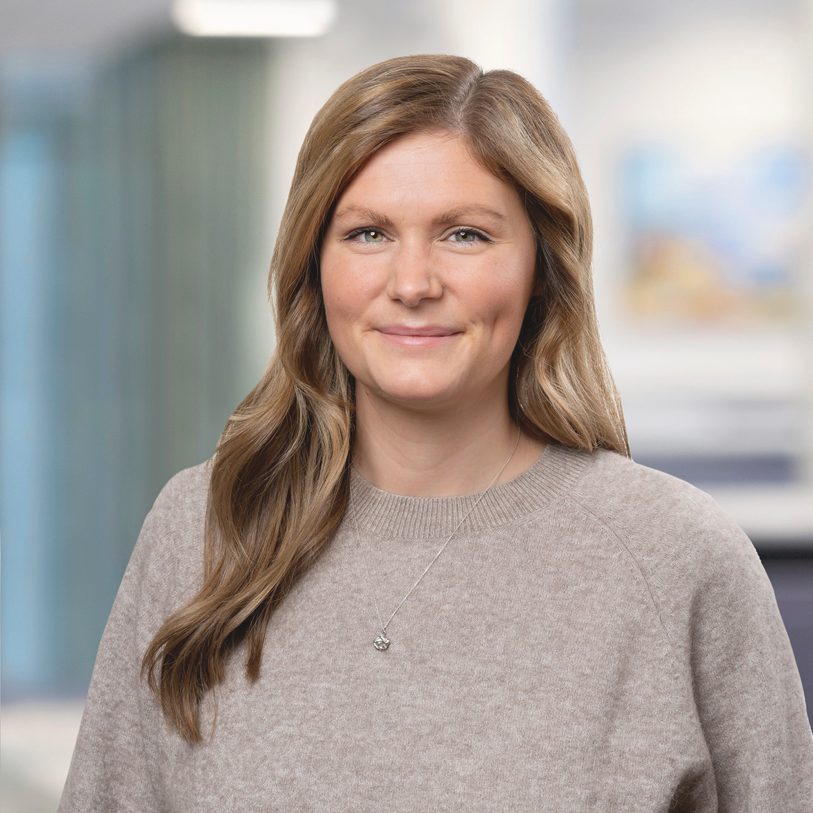 Klara Motavaf_EFFSO introduktionsprogram Porträtt på en leende ung kvinna med långt hår och grå tröja.