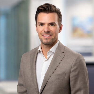 Porträtt på en ung man i vit skjorta och beige kavaj.