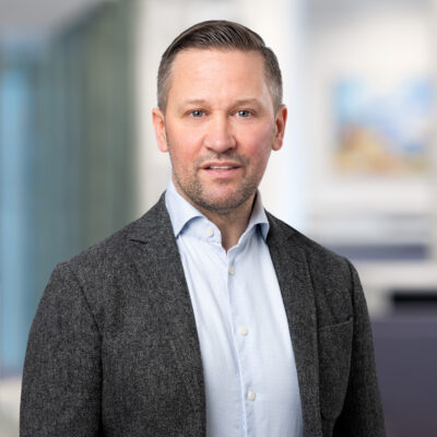 Porträtt på en man i ljusblå skjorta och mörk kavaj.