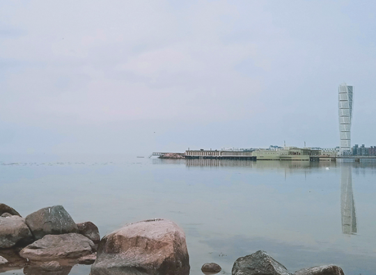 Bild tagen från vattnet på Turning Torso i Malmö i svag dimma.