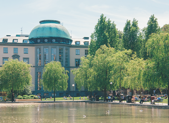 Bild på ena fasaden av Handelshögskolan i Stockholm,d en som vetter ut mot dammen.