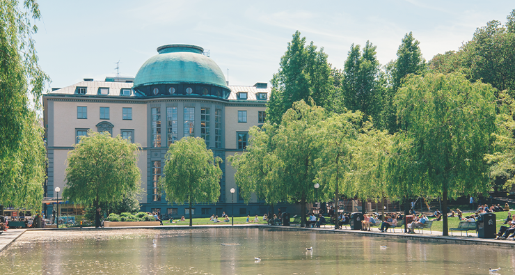 Bild på ena fasaden av Handelshögskolan i Stockholm,d en som vetter ut mot dammen.